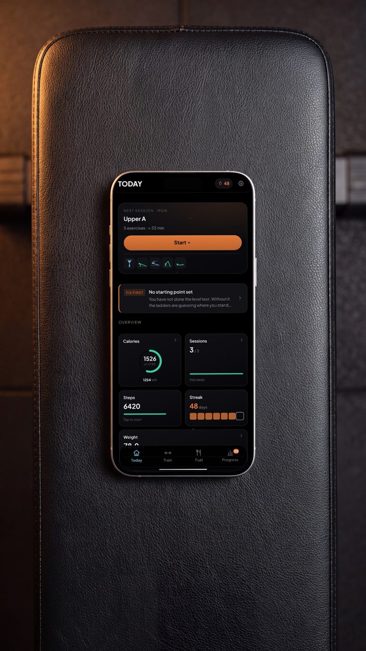 The VALKR app on a phone lying on a black leather gym bench
